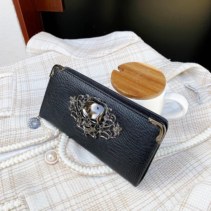 A black leather wallet with silver detailing rests on a cream textured fabric next to a white mug.