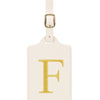 Étiquette de bagage en cuir crème rectangulaire avec une lettre F brodée en or et un clip métallique argenté.
