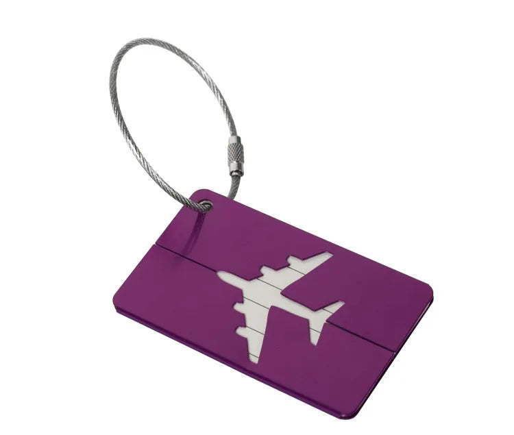 A purple aluminum luggage tag with a white airplane silhouette and a silver cord.