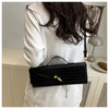 A woman holds a black crocodile-embossed PU leather clutch bag against a white top.