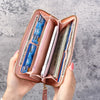 A pink fashion zipper wallet is open, displaying various cards and cash inside.