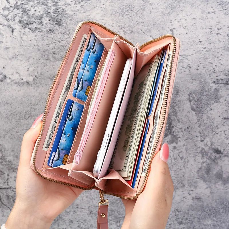 A pink fashion zipper wallet is open, displaying various cards and cash inside.