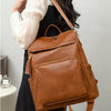 A brown leather vintage tassel backpack worn by a person, featuring anti-theft details.