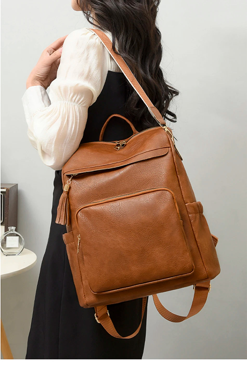 A brown leather vintage tassel backpack worn by a person, featuring anti-theft details.