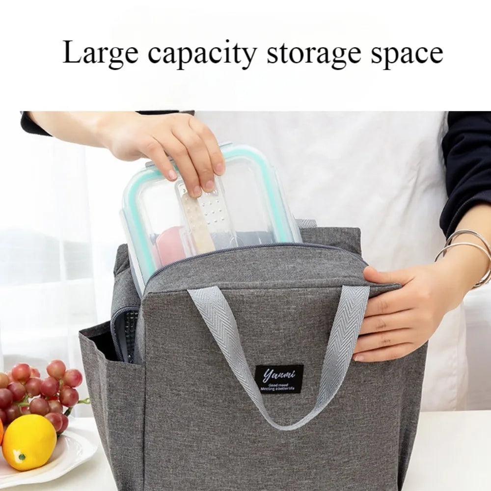 A hand is placing a clear plastic container into a gray canvas tote bag with double pockets.