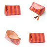 A square, glossy orange and brown striped cosmetic travel pouch with a dangling fringe.