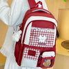A red and white patterned backpack with a laptop compartment worn by a person in a white dress.
