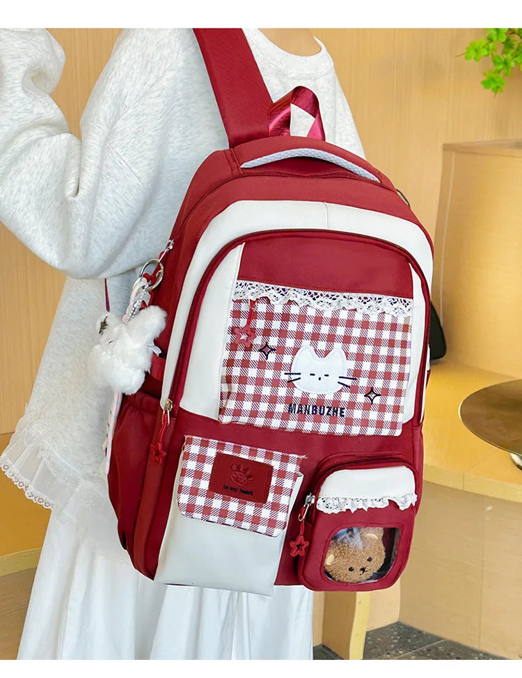 A red and white patterned backpack with a laptop compartment worn by a person in a white dress.