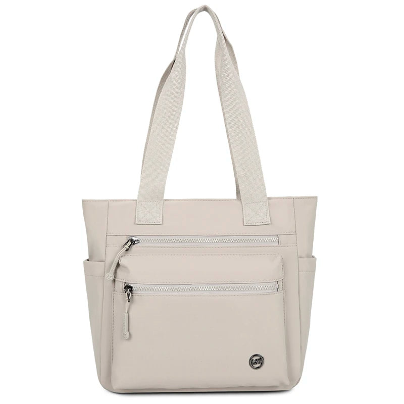 A beige canvas tote bag with two zippered pockets and light beige straps.
