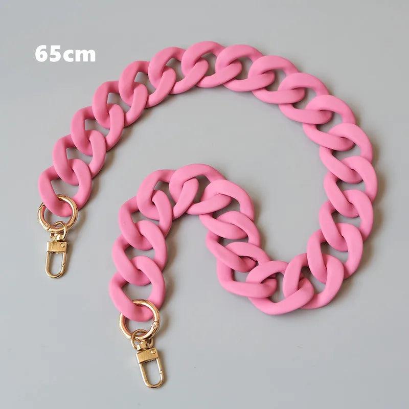 Bracelet ou collier en résine rose mat de 65cm, exposé sur un fond gris.
