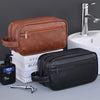 A brown leather toiletry bag and a black leather toiletry bag are displayed next to a sink and a faucet.