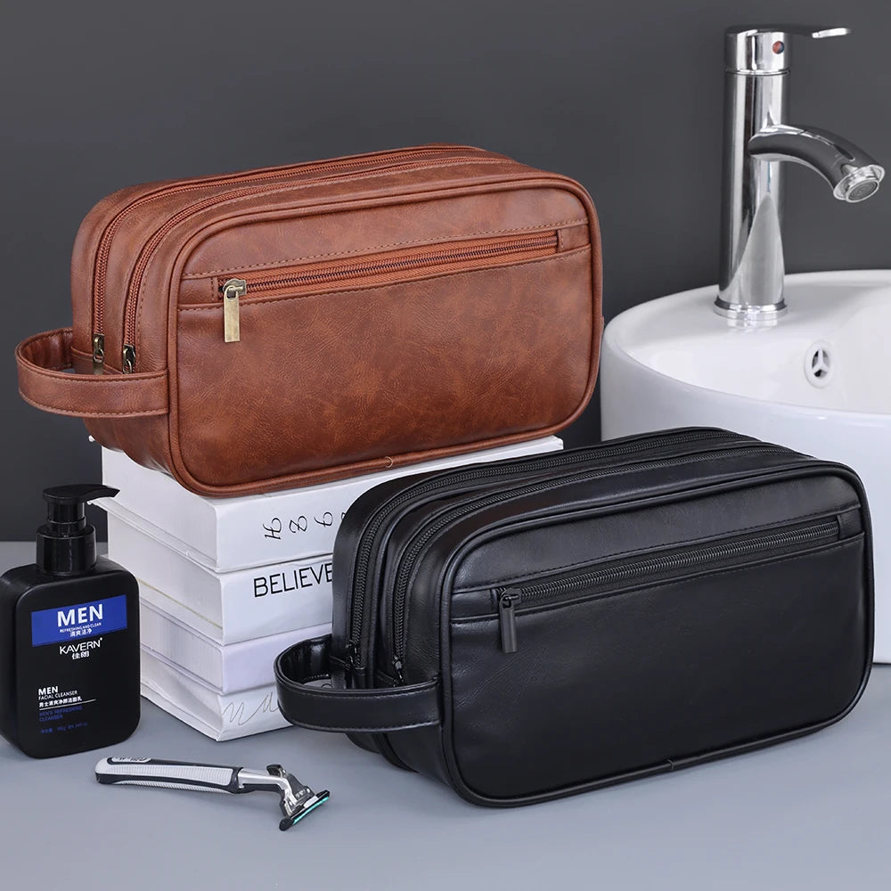 A brown leather toiletry bag and a black leather toiletry bag are displayed next to a sink and a faucet.