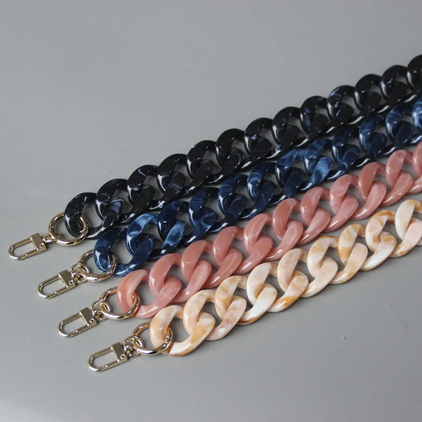 A collection of acrylic resin detachable bag chain straps in various shades of blue, purple, and pink laid out diagonally.