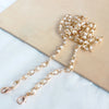 A delicate gold chain strap made of small white pearls resting on a beige rectangular surface.