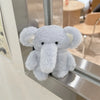 A soft gray plush elephant toy is displayed in a silver case.
