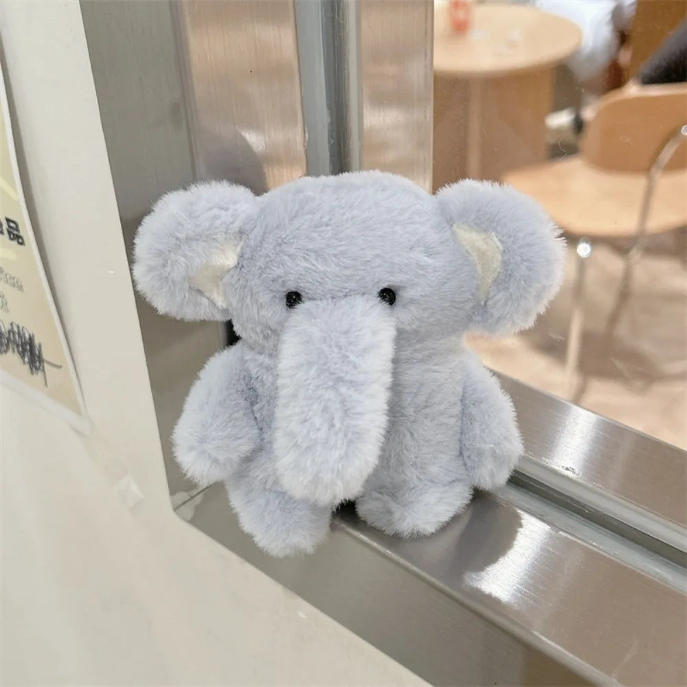 A soft gray plush elephant toy is displayed in a silver case.