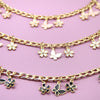 Goldkette mit kleinen Blumenschmuckern und einem Schmetterlingscharm auf rosa Hintergrund