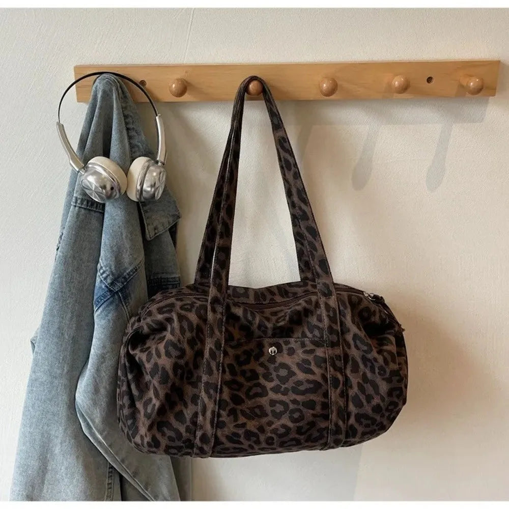 A brown leopard print canvas tote bag hanging on a wooden rack.