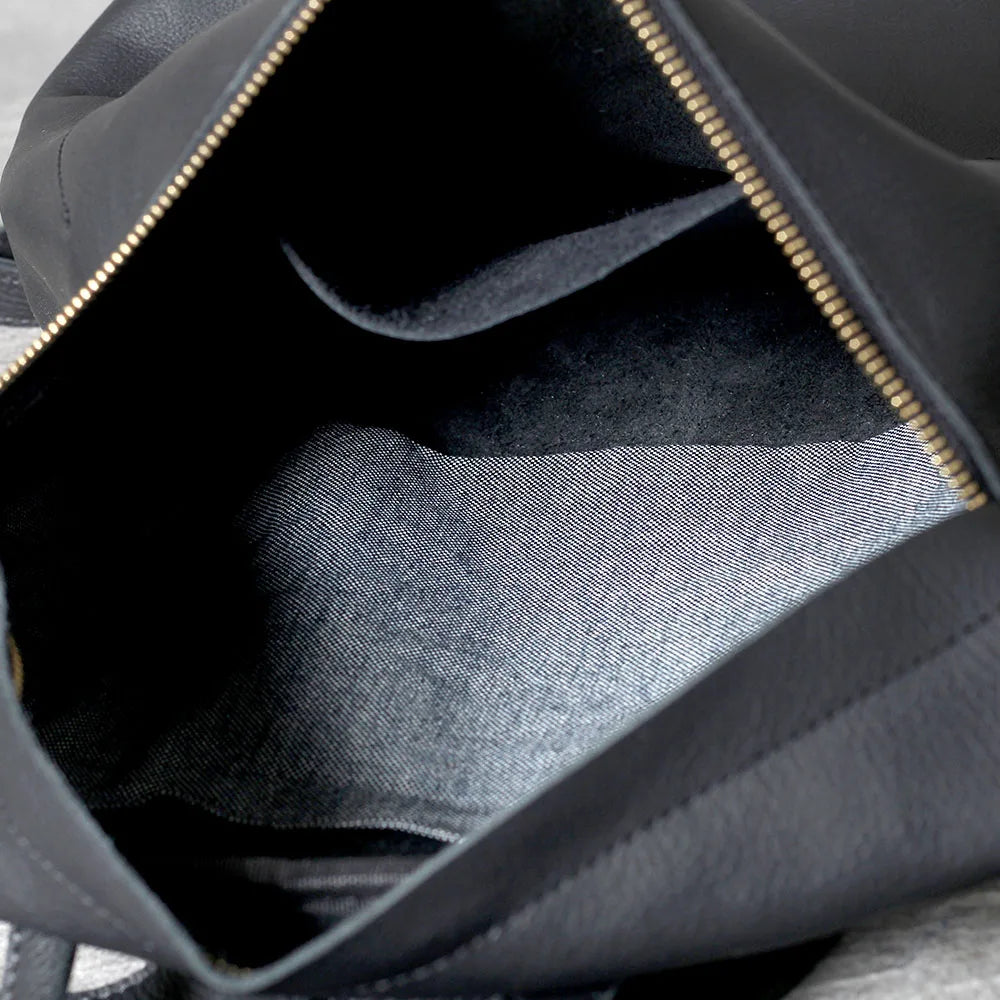 Interior view of a black full-grain leather backpack showing the lining and zipper details.