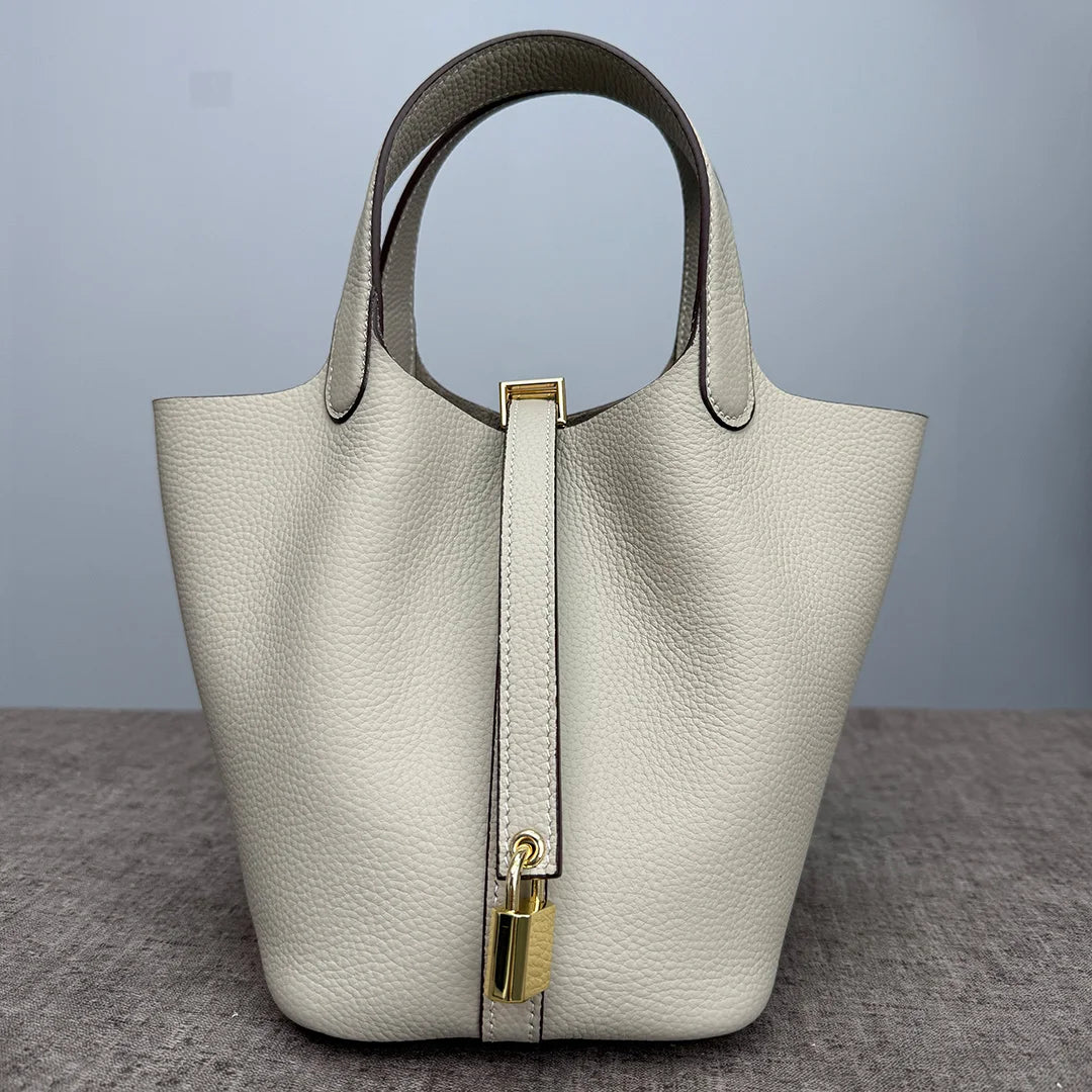 A light beige classic genuine leather bucket bag with a smooth texture and gold-toned hardware.