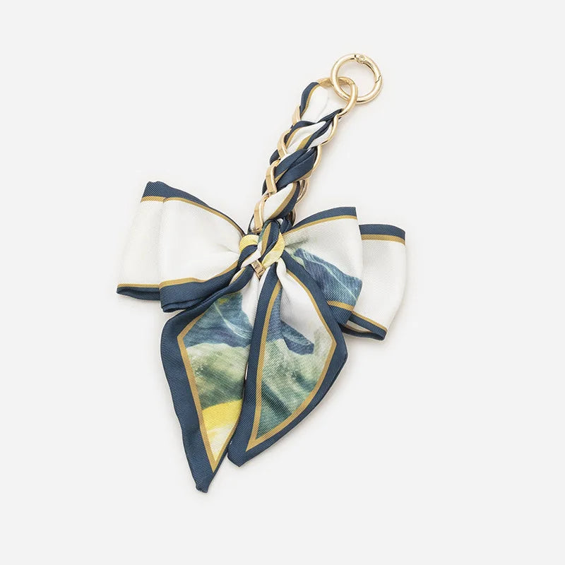 A navy and white fabric bow bag with a gold chain strap extension.