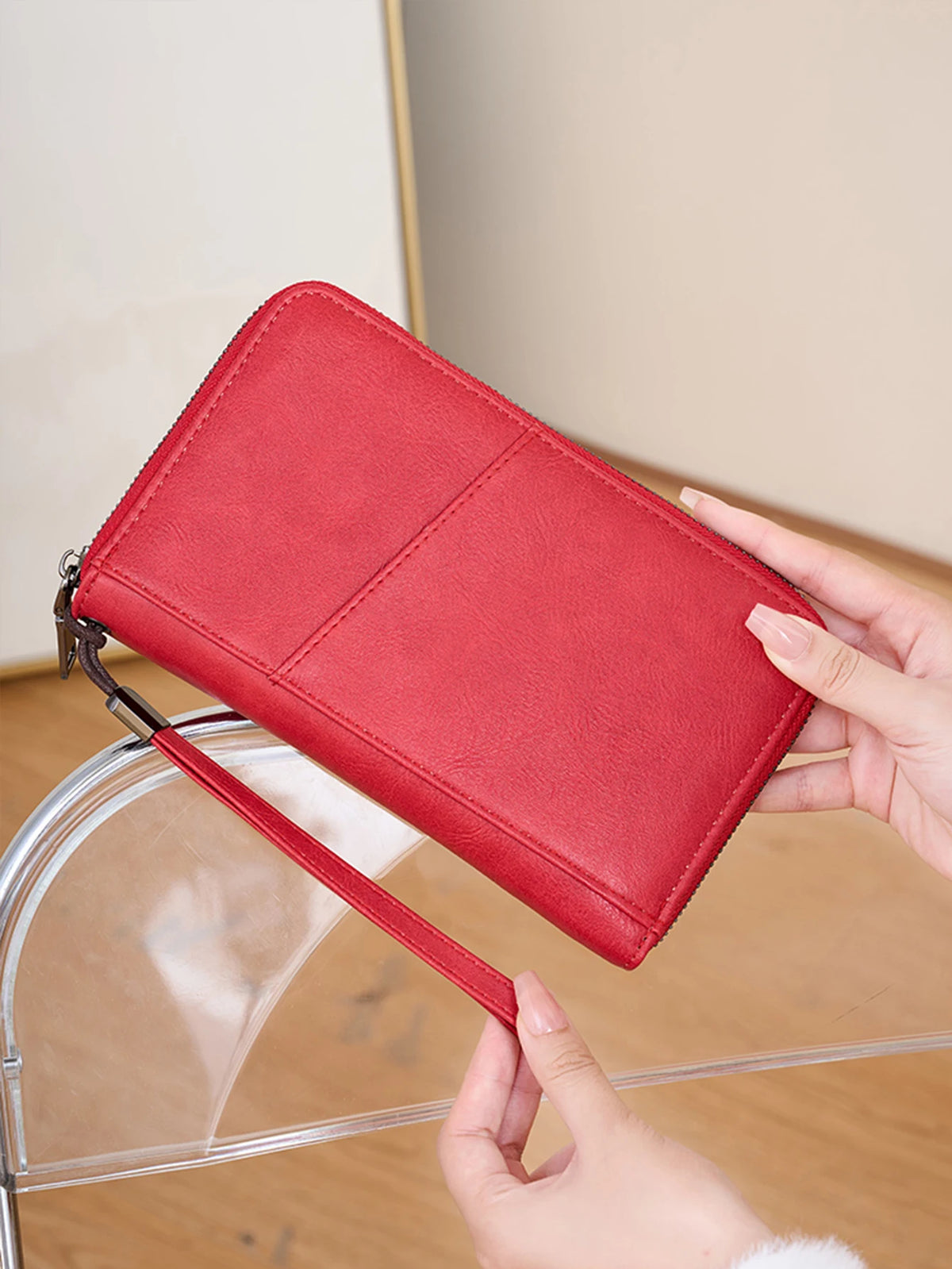 A red leather RFID blocking travel wallet is held by a hand above a clear acrylic stand.