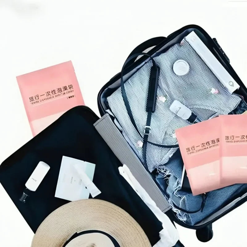 A black suitcase contains a set of pink disposable bathtub liners and a straw hat.