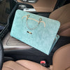 A teal laptop sleeve with a gold chain strap is placed on the center console of a car interior.