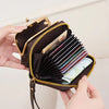 A close-up of a black leather accordion card holder wallet with gold accents and a subtle pattern, being held by a hand.
