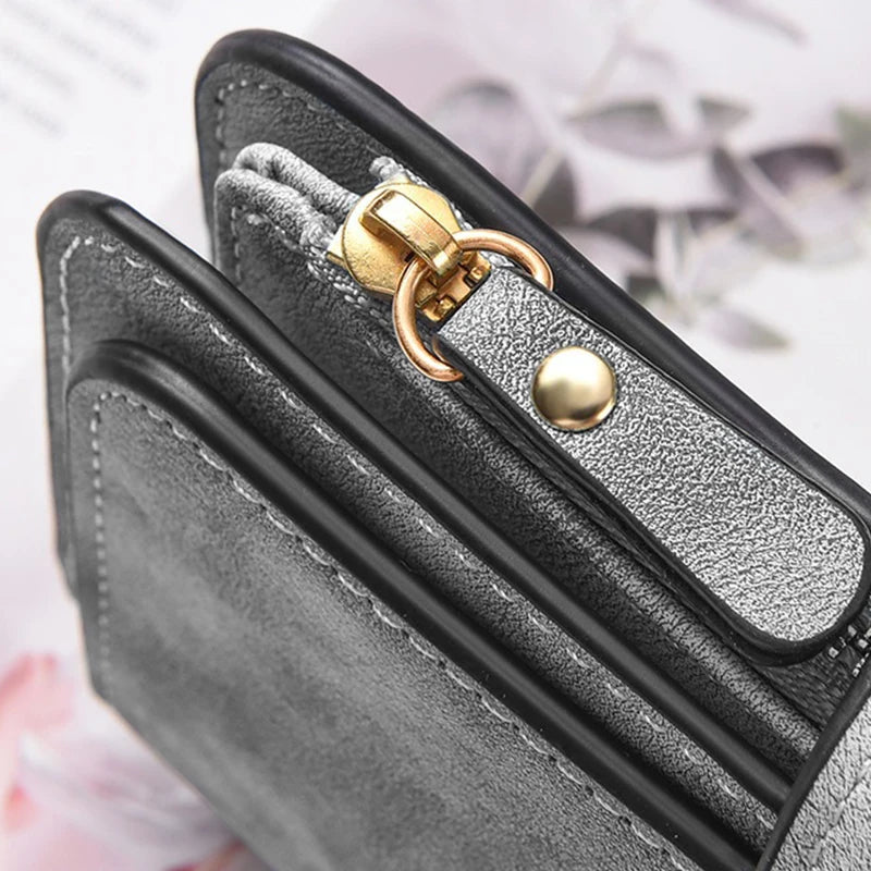 A close-up of a black leather long zipper handbag coin purse with gold hardware and silver accents.