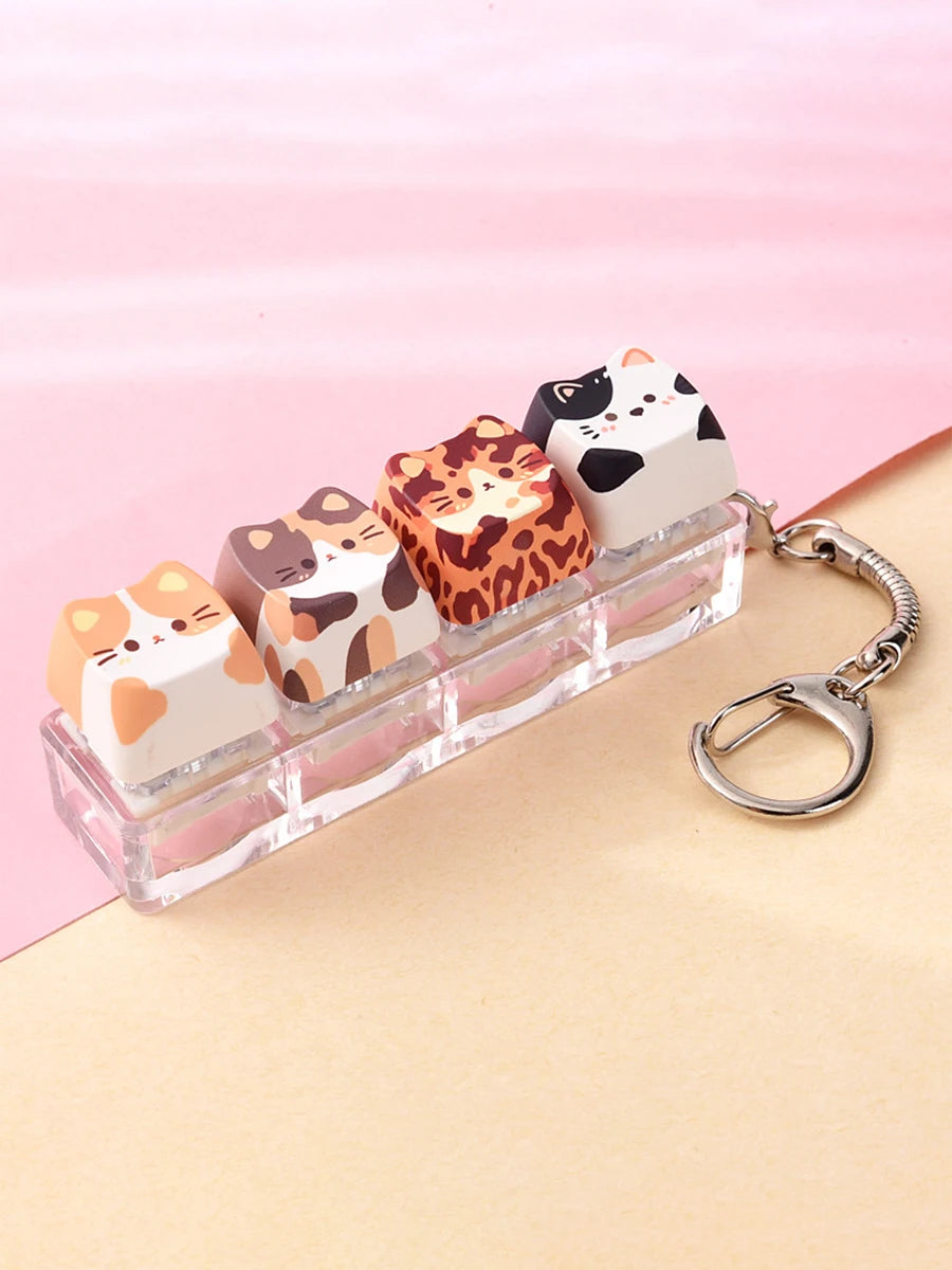 A collection of acrylic kawaii cat keycaps and fidget toys in various orange, white, and black leopard print designs displaye