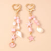 Gold heart-shaped keychain featuring a starfish and pearl accents with pink and white striped beads.