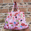 A pink reusable shopping bag filled with various colorful mushrooms against a brick background.