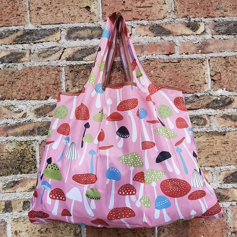 A pink reusable shopping bag filled with various colorful mushrooms against a brick background.