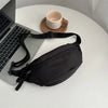 A black anti-theft waist pack is displayed next to a laptop and a ceramic mug on a white surface.