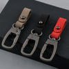 Three leather keyring keychains in shades of brown, black, and red displayed on a dark surface.
