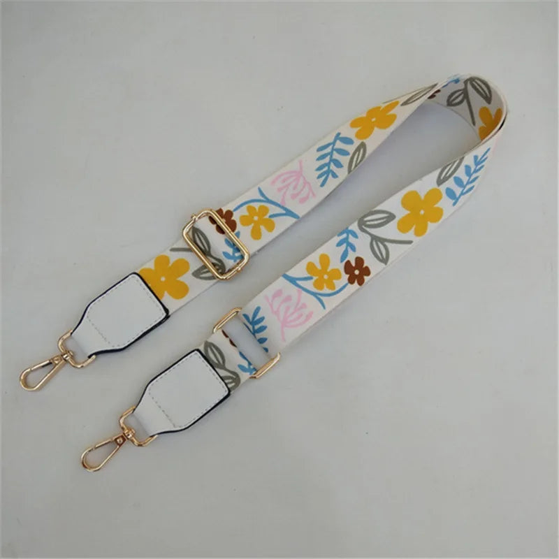 Sangle réglable à motif floral beige et jaune pour sacoche de type messenger.