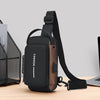 A black men's Oxford sling chest bag with a brown strap and a phone pocket resting on a wooden surface.