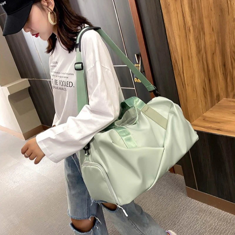A person is carrying a light green duffel bag with a black strap in a store setting.