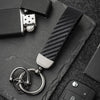 A close-up shot of a carbon fiber leather keychain attached to a dark surface.