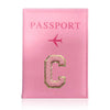 A pink leather passport holder with a gold initial C and a pink airplane symbol.