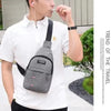 A man wearing a white shirt holds a gray waterproof crossbody fanny pack and uses an earbud.