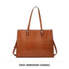A brown croc-embossed cognac laptop tote bag with leather handles.