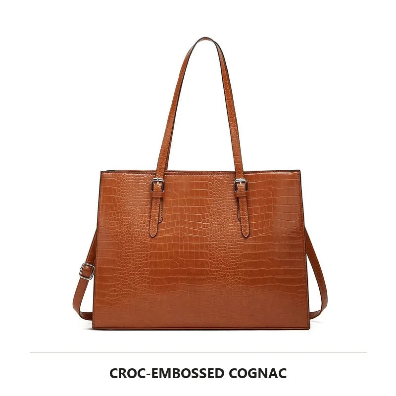 A brown croc-embossed cognac laptop tote bag with leather handles.
