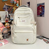 A white lightweight nylon college backpack with a gray strap and a small tag on the front pocket.