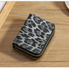 A black and gray leopard print double zipper wallet resting on a wooden surface.