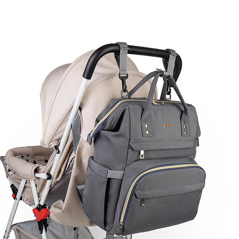 Graue, große Still- und Muttermilch-Windeltasche mit schwarzem Griff neben einem Babytragetuch.