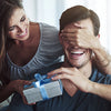 A woman and a man are laughing together while a woman holds a gift box for a slim metal card holder.