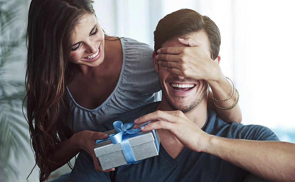A woman and a man are laughing together while a woman holds a gift box for a slim metal card holder.
