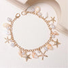 Gold layered chain necklace featuring pearl and seashell charms
